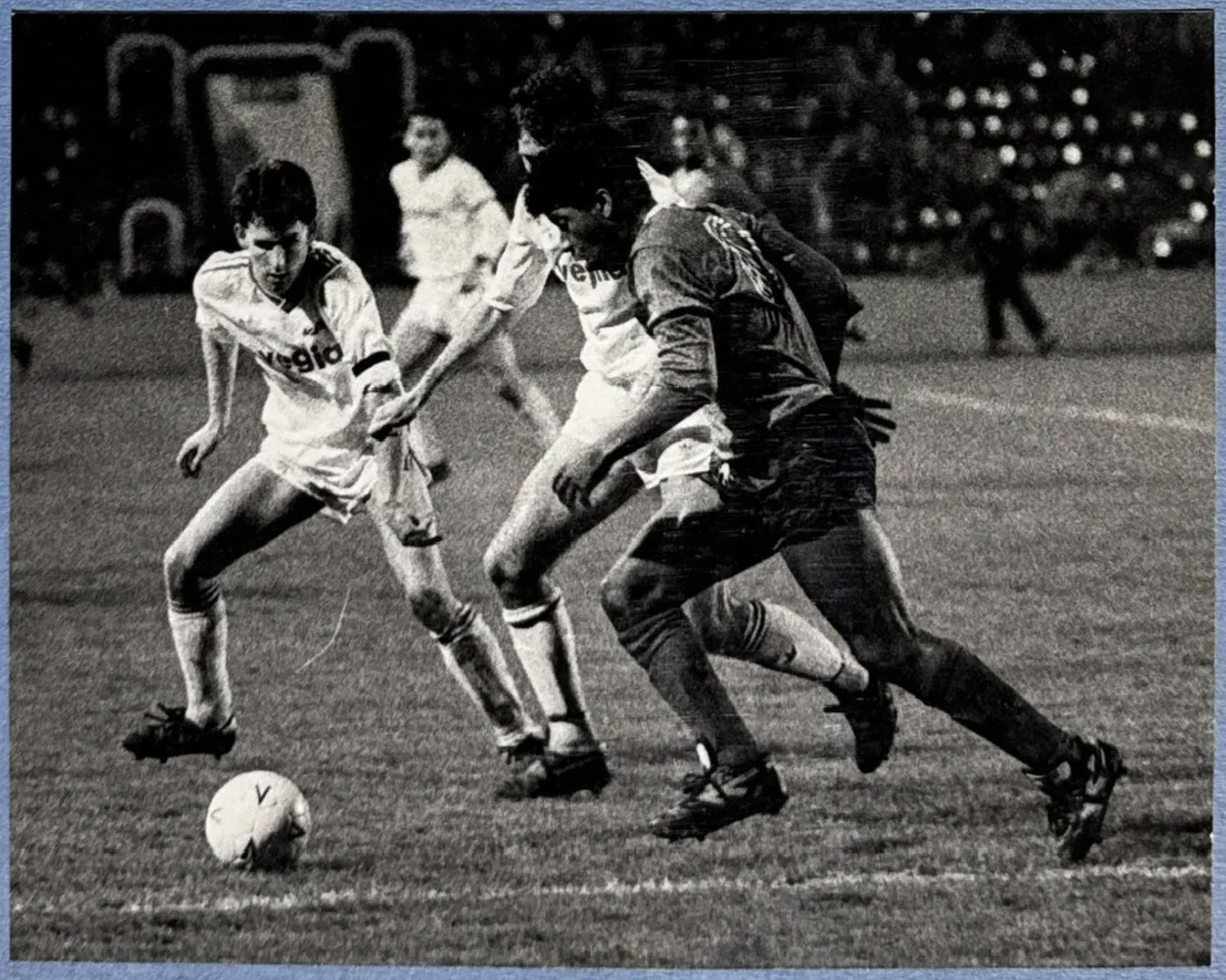 Mark Rosegreen in action during a floodlit match, holding off two defenders