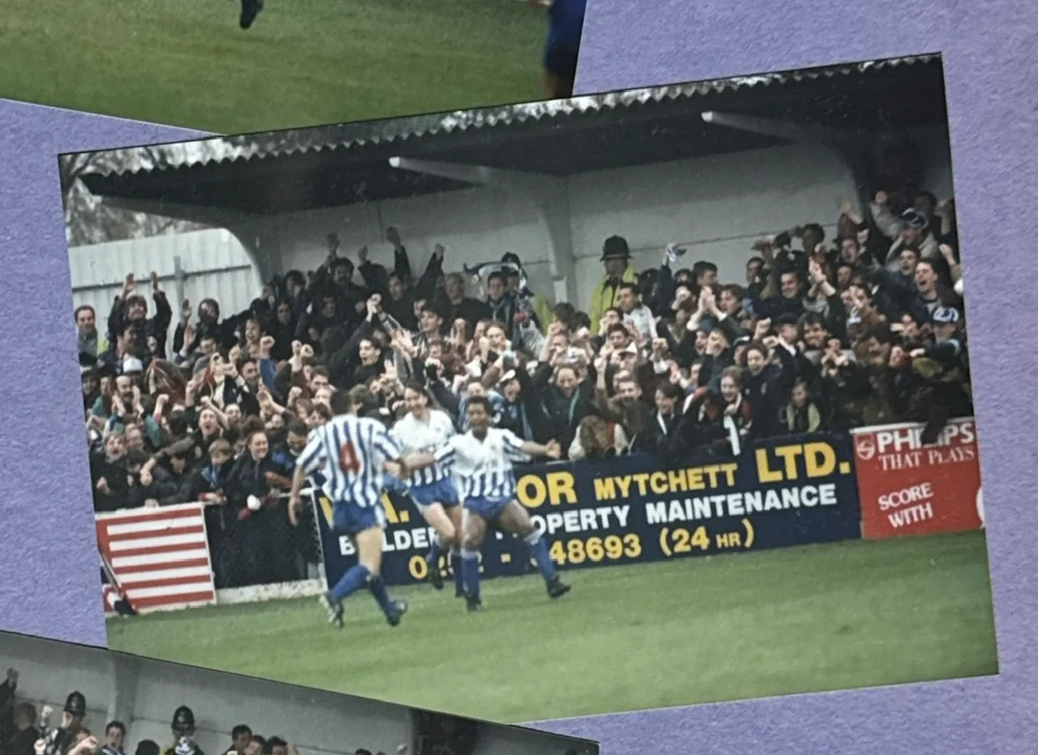Nuneaton Borough players in blue and white stripes celebrate a goal in front of a large jubilant crowd