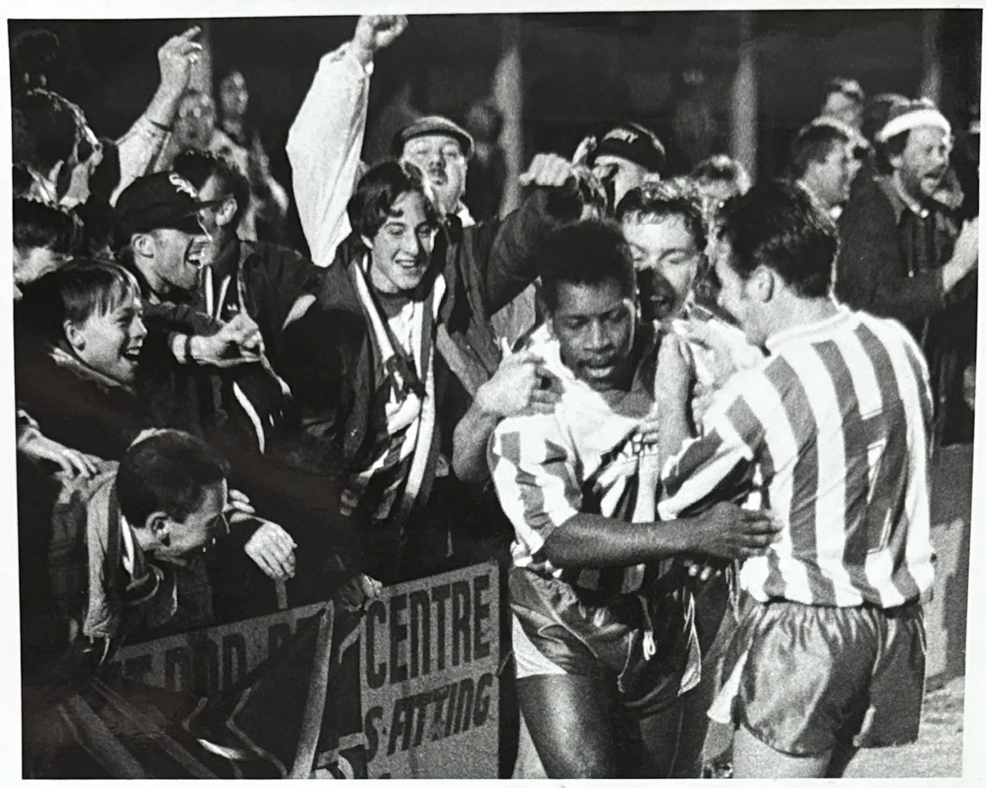 Mark Rosegreen celebrates a goal, mobbed by teammates and supporters
